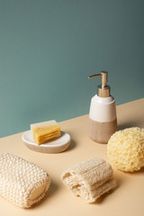 Fototapeta na wymiar Sponges with liquid soap dispenser and soap dish on beige and grey, zero waste concept