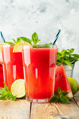 Watermelon slushie with lime and mint, summer refreshing drink in tall glasses on a light blue background. Sweet cold smoothie