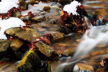 Small flowing river in winter with rocks.