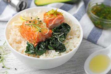 Tasty salmon with rice and spinach on white wooden table