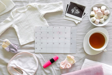 Calendar with the expected date of birth of baby, different baby clothes and ultrasound scan, pregnancy and birth concept