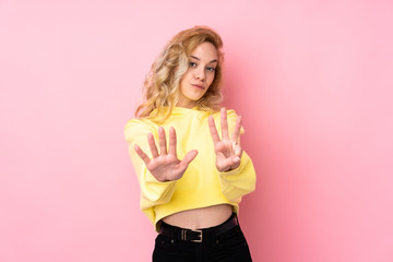 Young blonde woman wearing a sweatshirt isolated on pink background counting eight with fingers