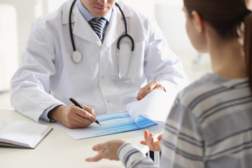 Doctor consulting patient at desk in clinic, closeup