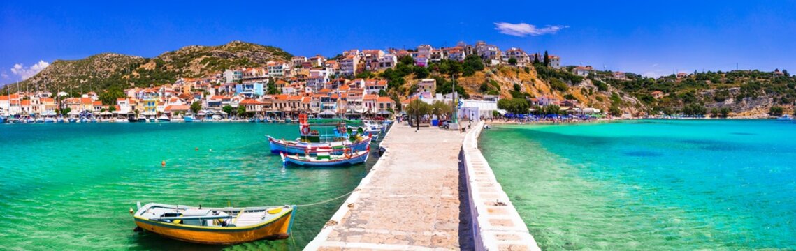 Pythagorion town Samos island Greece, scenic view of stone bridge pier between turquoise sea and traditional boats. Panoramic landscape of harbor in Aegean sea. Ultra high resolution wide panorama.