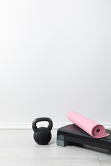 step platform, kettlebell and pink fitness mat on floor at home