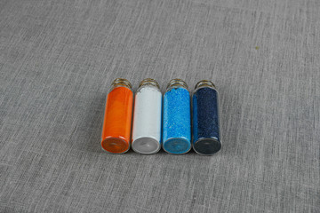 Blue, red, white and indigo powder and crystalls crystals in small bottles on gray linen background