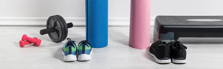 Zelfklevend Fotobehang panoramic shot of yoga mats, sneakers, step platform and sport equipment on floor at home © LIGHTFIELD STUDIOS