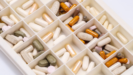 plastic medicine organizer with pills and capsules, medicines for health, pharmaceutical health care and sciences concept, shallow depth of field