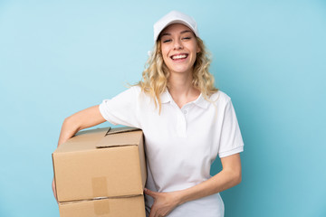 Young delivery woman isolated on blue background laughing