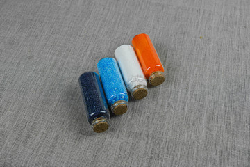 Blue, red, white and indigo powder and crystalls crystals in small bottles on gray linen background