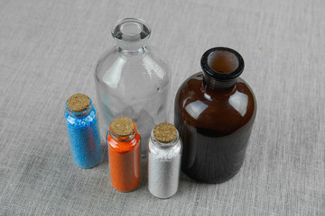 Blue, red and white powder and crystalls crystals in small bottles on gray linen background