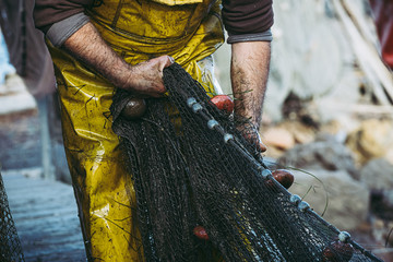 Mains d'un pêcheur en train de ranger ses filets de pêche