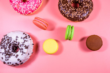 Fresh glazed donuts and french macaroons isolated on a pink background