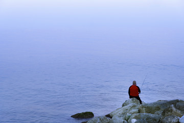 Old Man Fishing In The Mediterranean Sea With Fog