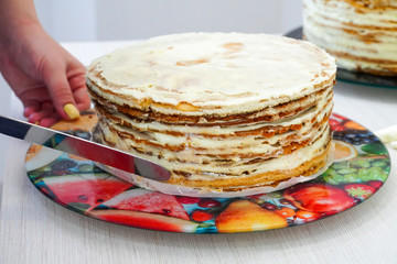 Cook - Confectioner. Cooking and leveling festive multilayer birthday cakes. Scones are smeared with whipped cream.