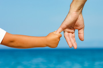 happy dad holds the hand of a child by the greek sea in nature