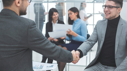 close up. smiling colleagues shaking hands with each other