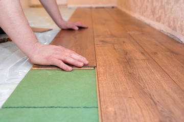 Man installs a laminated wooden floor. Repair concept.