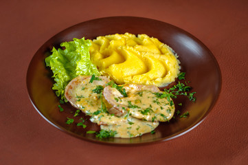 Pork cutlets with mashed potatoes in a plate on a brown table