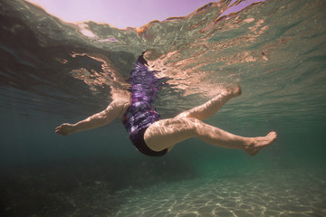 Cuerpo de una mujer bañandose en el mar bajo el agua