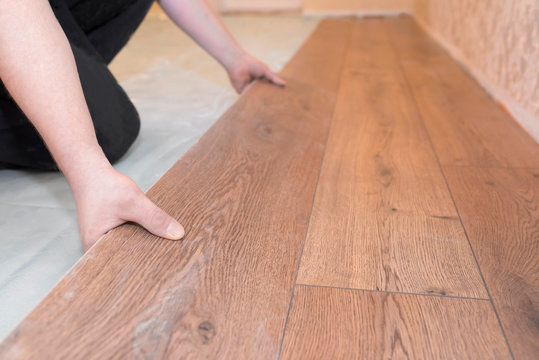 Worker installs a wooden parquet floor. Repair concept.