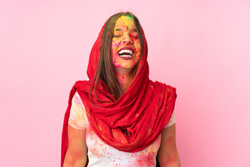 Young Indian woman with colorful holi powders on her face isolated on pink background laughing