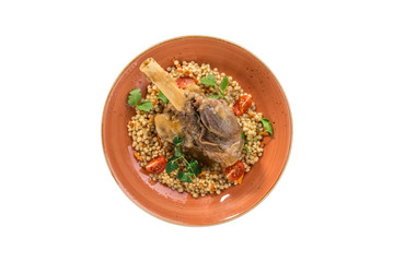 Roast lamb shank with peas on orange plate isolated on white background