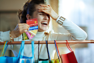 cheerful female near shopping bags with fan of credit cards - Powered by Adobe