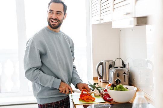 Image of pleased handsome man smiling and making lunch