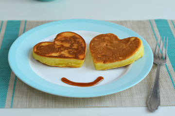Two american pancakes on blue plate for healthy breakfast on wooden table.Breakfast on Valentine's Day or 8 March - pancakes in the shape of a heart.
