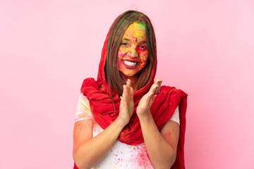 Young Indian woman with colorful holi powders on her face isolated on pink background applauding after presentation in a conference