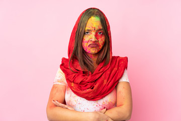 Young Indian woman with colorful holi powders on her face isolated on pink background feeling upset