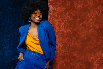 African American fashionable woman wearing yellow sunglasses, top, classic blue suit. Young...