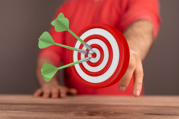 hand holding a target with darts hitting the center over white background. Concept of .