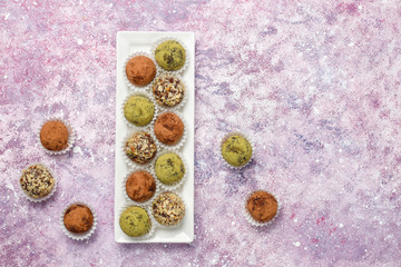 Obraz na płótnie Canvas Homemade healthy vegan raw energy truffle balls with dates and walnuts,matcha powder,cocoa powder on light background