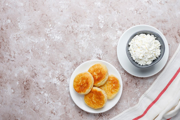 Cottage cheese pancakes.Russian syrniki or sirniki, cottage cheese fritters or pancakes with a bowl of fresh homemade cottage cheese on light background