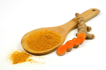 Turmeric powder in wooden spoons and turmeric roots isolated on a white background, used as a tonic for the body and turmeric supplements or as an ingredient in food.