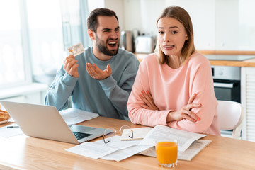 Portrait of annoyed couple having argument while holding credit card