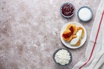 Cottage cheese pancakes.Russian syrniki or sirniki, cottage cheese fritters or pancakes with a bowl of fresh homemade cottage cheese on light background