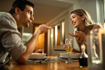 Below view of happy couple communicating during a meal at dining table.