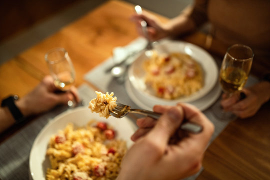 Close-up Of Couple Eating Pasta For Dinner At Dining Table.