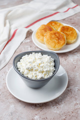 Cottage cheese pancakes.Russian syrniki or sirniki, cottage cheese fritters or pancakes with a bowl of fresh homemade cottage cheese on light background