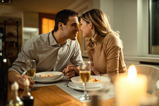 Young couple in love showing affection during a meal at dining table.