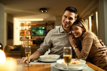 Young couple in love sitting embraced at dining table.