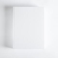 Mockup of closed blank square book at white textured paper background
