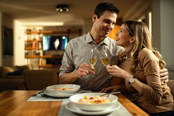 Happy couple toasting with Champagne while embracing at dining table.