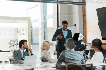 Fototapeta premium handsome african american businessman showing robot to multicultural colleagues in office