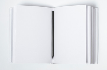 Mockup of closed blank square book and black pencil at white textured paper background