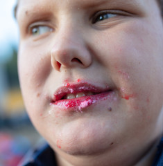 The boy eats red cotton candy