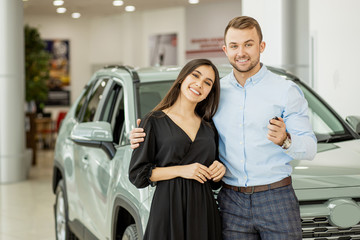 Fototapeta na wymiar young caucasian couple buy new car, automobile in dealership, showroom. customers looking for preferred beautiful car